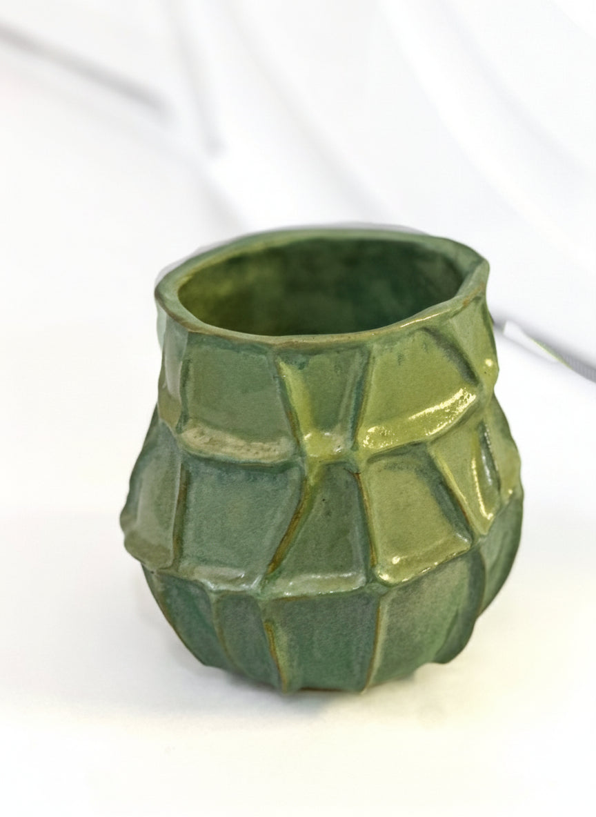 Green ceramic vase with textured surface on a white background